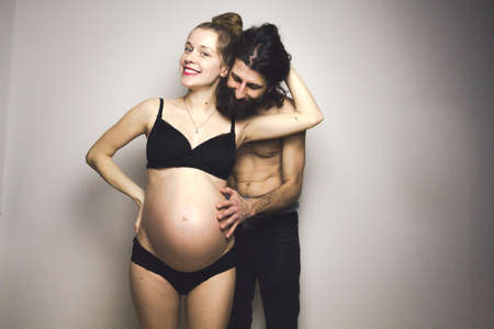beautiful pregnant woman and her handsome boyfriend posing in lingerieの写真素材