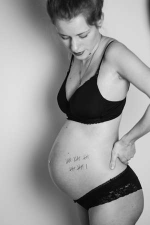 pregnant woman with tally list of 26 weeks on her bellyの写真素材