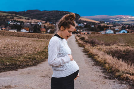 young pregnant woman outdoors in rural landscapeの写真素材