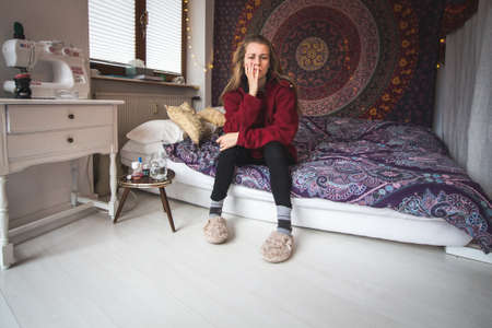 sad and depressed young woman sitting on her bedの写真素材