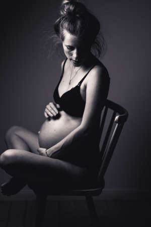 portrait of a beautiful sensual pregnant woman sitting on a chairの写真素材