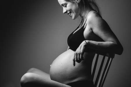 happy pregnant woman smiling and sitting on a chairの写真素材