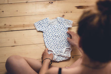 pregnant woman in lingerie sitting on hardwood floorの写真素材