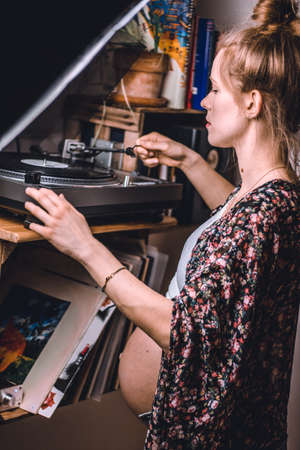 pregnant woman putting a vinyl record on her turntableの写真素材