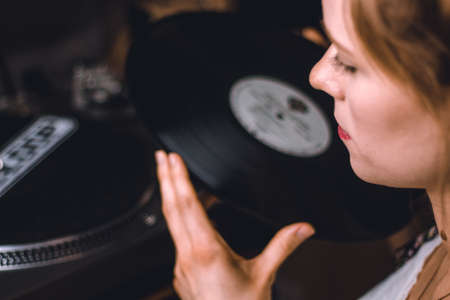 young woman putting on a vinyl record at homeの写真素材