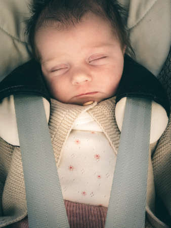 infant baby sleeping in car with seatbelt onの写真素材