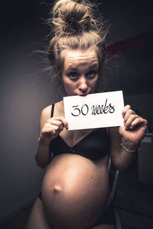 beautiful young woman being pregnant for 30 weeks and waiting on giving birthの写真素材
