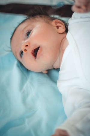 blue eyed baby lying on back on a blue blanket
