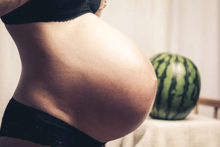 huge pregnant belly compared to a watermelonの写真素材