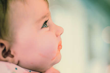 baby with dirty mouth eating babyfoodの写真素材