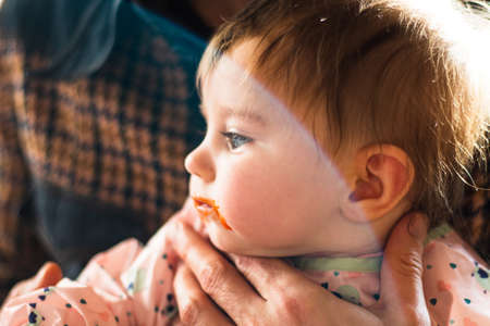 baby with dirty mouth eating babyfoodの写真素材