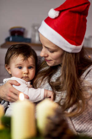 mother with santa hat holding her baby at christmas time