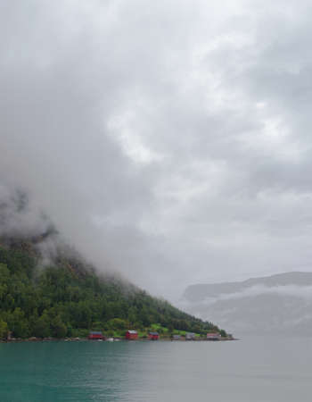tiny red boathouses on a cloudy morning in Norwayの写真素材