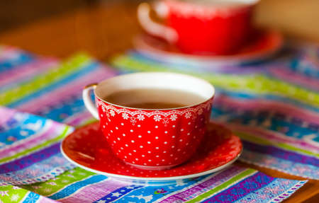 Hot tea in a red Cup with a watch over on the color napkinの写真素材