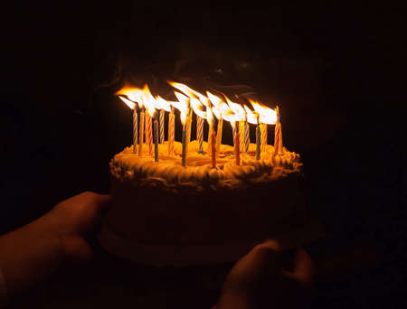 Anniversary cake with burning candles on dark backgroundの写真素材