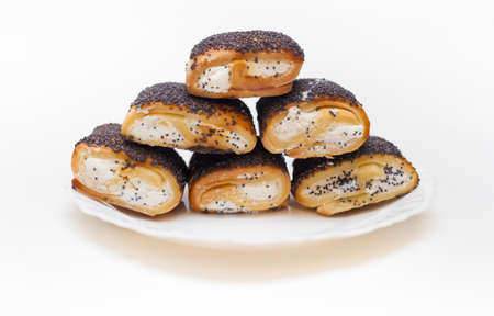 butter cookies with filling and poppy seeds on a white plate on a white background