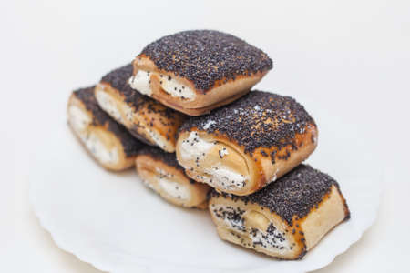 butter cookies with filling and poppy seeds on a white plate on a white backgroundの写真素材