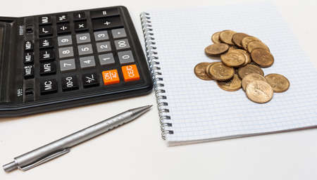 Pen, Notepad, calculator and coins on a white backgroundの写真素材