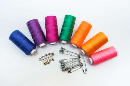 A set of colored threads on a spool "rainbow" with pins on a white backgroundの写真素材