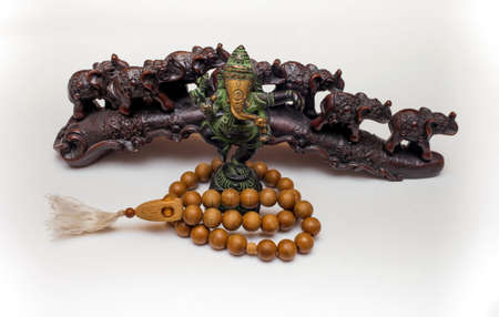 Indian Souvenirs: Bronze Ganesha, wooden beads and plastic elephants in the background on a white backgroundの写真素材