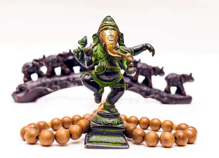Indian Souvenirs: Bronze Ganesha, wooden beads and plastic elephants in the background on a white backgroundの写真素材