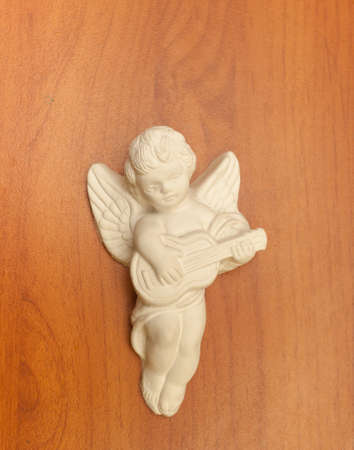 White toy "angel with a guitar" ceramic on a wooden tableの写真素材