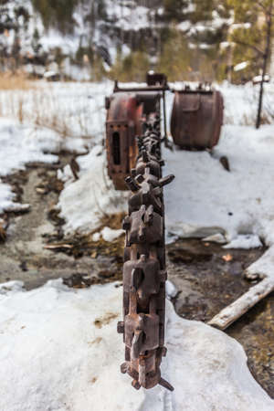 Abandoned industrial chain saw on the bottom of the quarry in winter