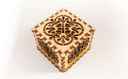 The box is made of plywood with a pattern cut by laser cutting on a white backgroundの写真素材