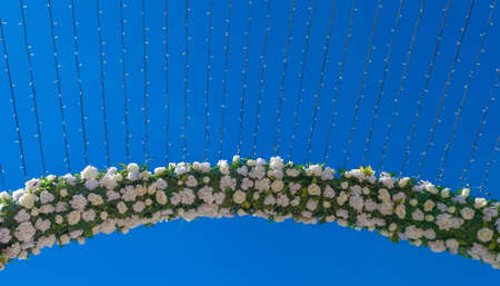 Arch of flowers with a lighting system on the background of blue skyの写真素材