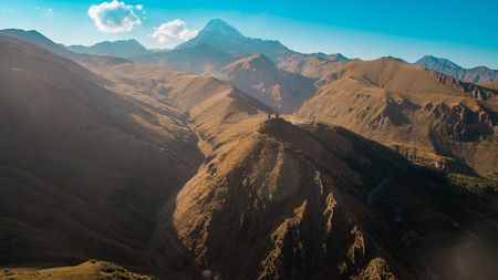 a church on top of the mighty mountains in Georgiaの写真素材