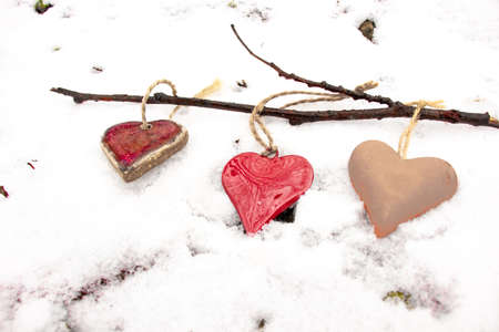 red reflective heart, red hearts in white snow on a tree branchの写真素材