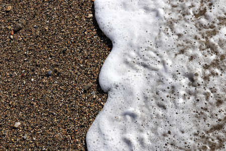 Beach sand with sea wave foam. Marine summer background.