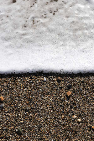 Sea wave foam on the beach sand. Marine summer background.