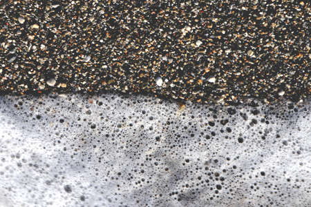 Sea little stone granules with wave foam. Sea background.の写真素材