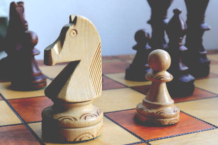 White horse and pawn chess figures background. Wood game chessboard.