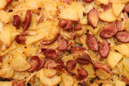 Fried potato grill lunch food background. Filling BBQ texture. Grilled potatoes slices with sausage slices and onions.の写真素材
