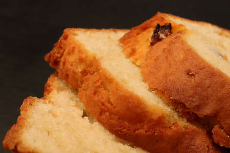 Sweet swirling roll bun with poppy and raisins slices. Filling background. Macro closeup.