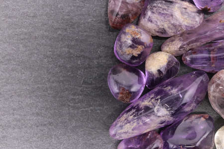 Rutilated amethyst jewel heap on black wood half background. Pile mineral pebbles texture. Place for text.の写真素材