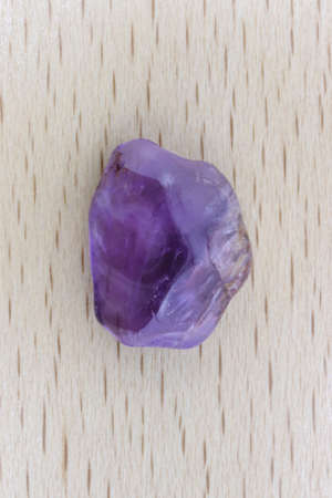 Rutilated amethyst jewel stone texture on varnished wood background. Macro closeup.
