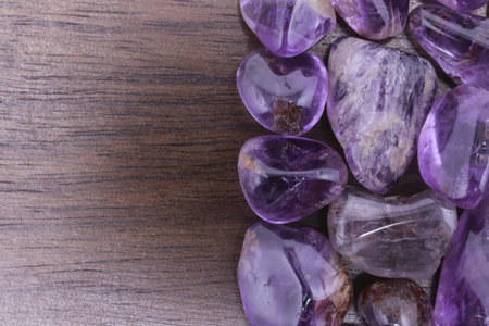Rutilated amethyst jewel heap on black wood half background. Pile mineral pebbles texture. Place for text.の写真素材