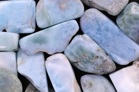 Larimar jewel heap on brown varnished wood half background. Pile mineral pebbles texture. Place for text.の写真素材
