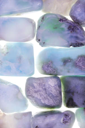 Larimar jewel heap on brown varnished wood half background. Pile mineral pebbles texture. Place for text.の写真素材