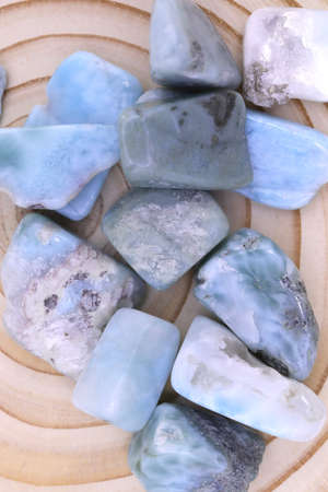 Larimar jewel heap on brown varnished wood half background. Pile mineral pebbles texture. Place for text.の写真素材