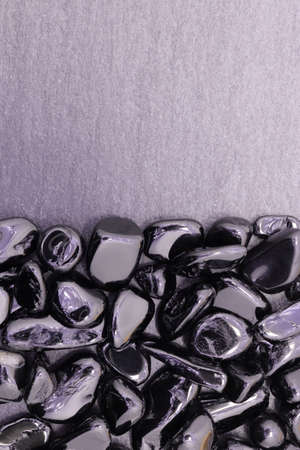 Black tourmaline jewel stone texture on light varnished wood background. Macro closeup.の写真素材