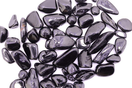 Black tourmaline jewel stone texture on light varnished wood background. Macro closeup.