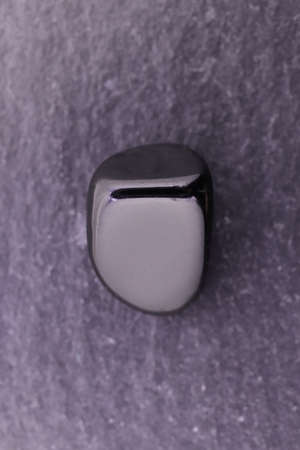 Black tourmaline jewel stone texture on light varnished wood background. Macro closeup.の写真素材