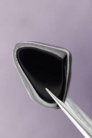 Black tourmaline jewel stone texture on light varnished wood background. Macro closeup.の写真素材