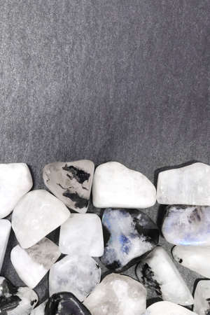 Moon stone jewel heap on black stone half background. Pile mineral pebbles texture. Place for text.の写真素材