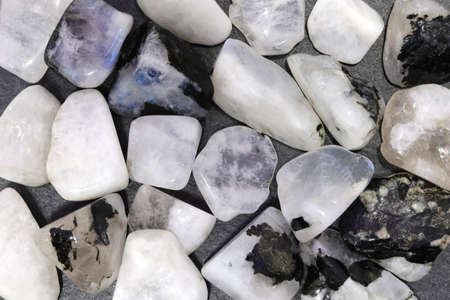 Moon stone heap jewel on brown varnished wood texture. Pile mineral pebbles background.の写真素材