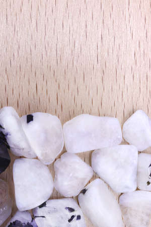 Moon stone heap jewel on brown varnished wood texture. Pile mineral pebbles background.の写真素材